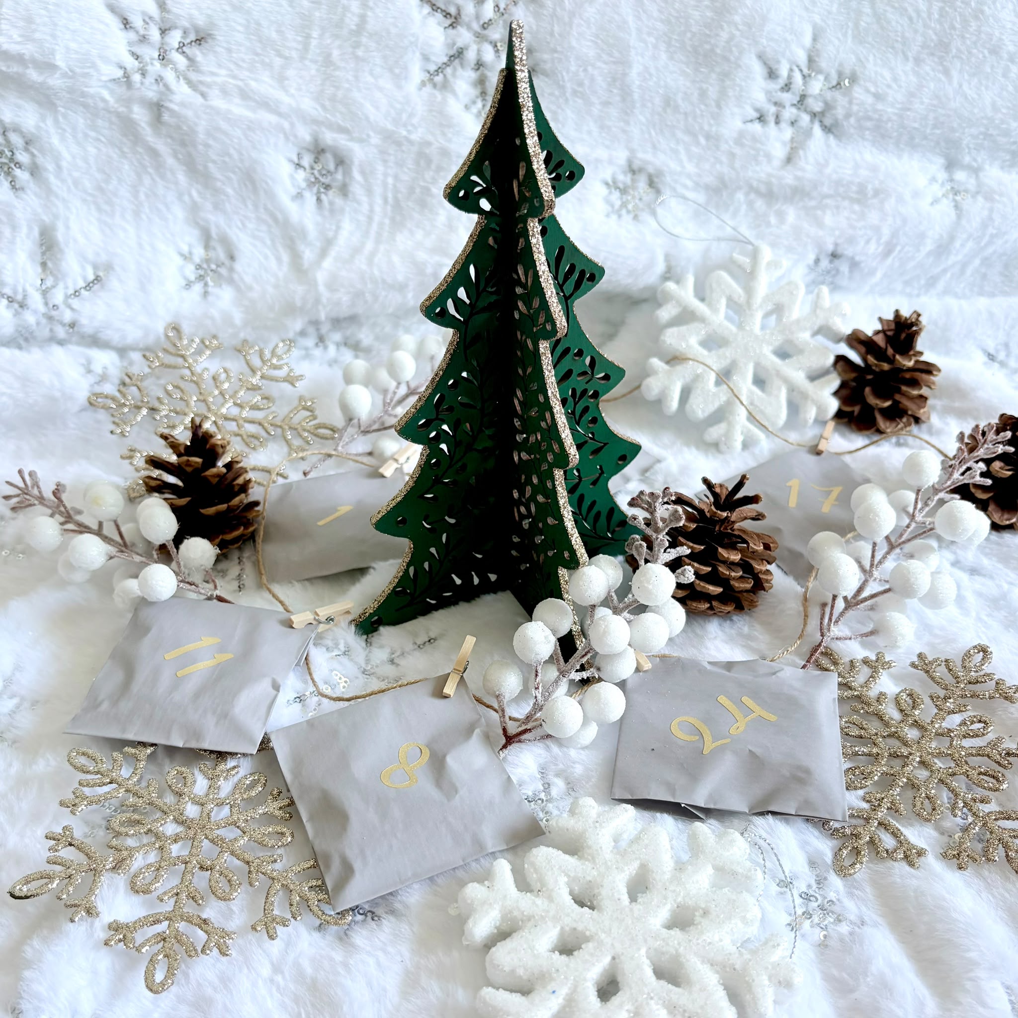 Festive Advent Calendar Contents Silver jewellery pouches, snowflakes and green wooden Christmas tree