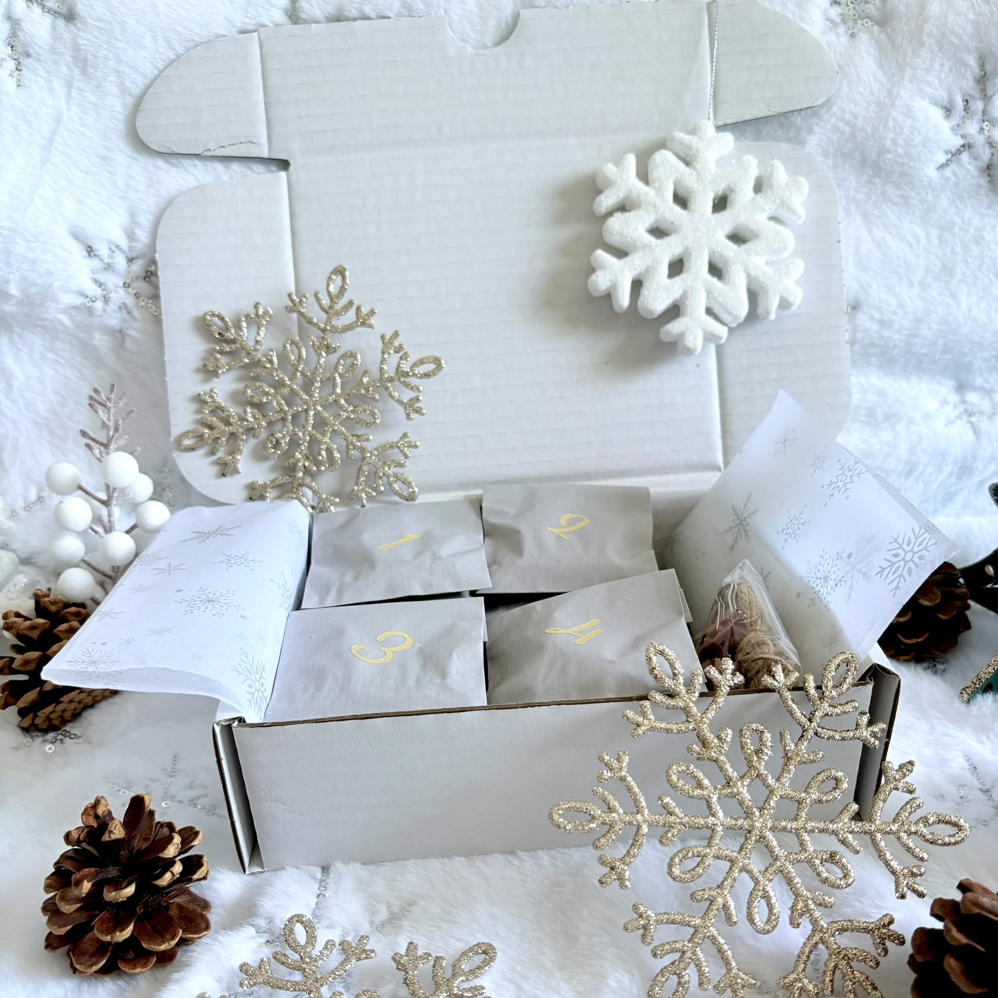 Advent Calendar Pouches containing bead kits in a box with Christmas snowflake decorations